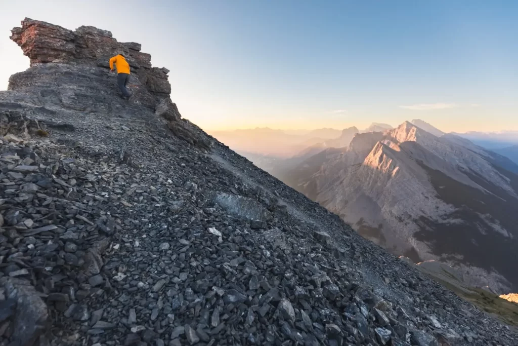 Ha Ling Peak is visible in the distance as a hiker makes the final ascent up East End of Rundle