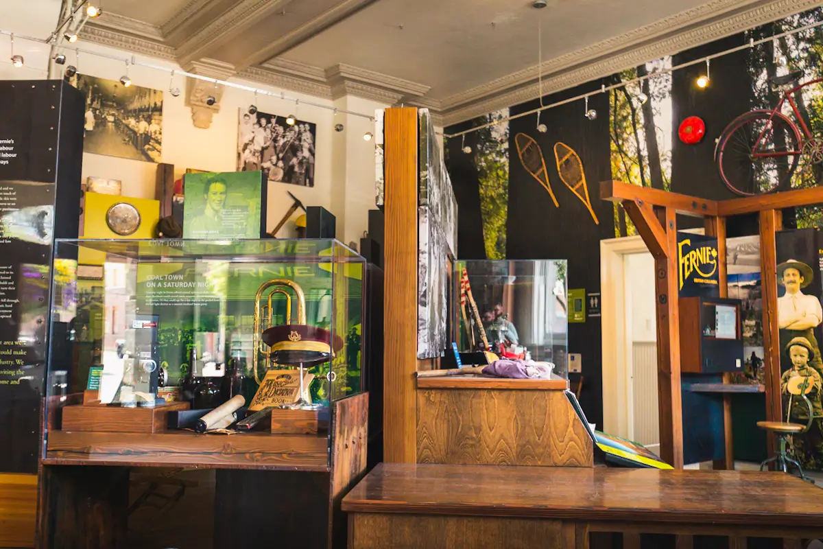 A small museum exhibit displays vintage items, historical photographs, and artifacts. Glass cases hold objects and placards—perfect for those seeking unique Fernie activities or looking for things to do in Fernie.