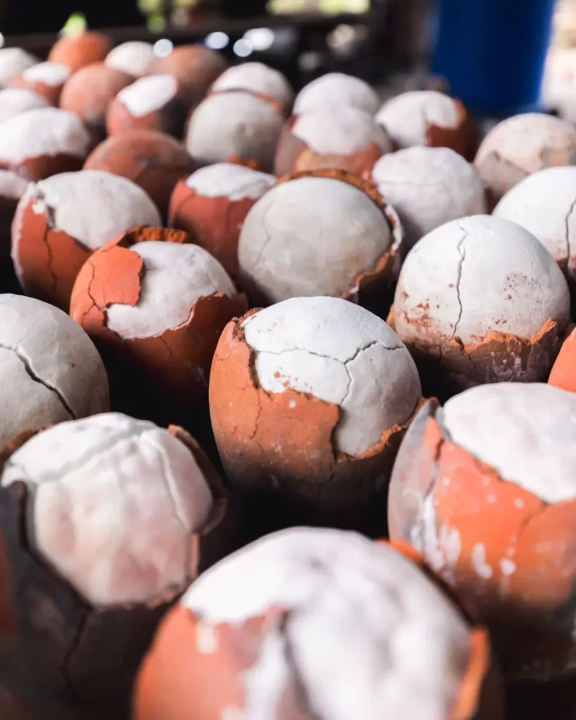 A close-up of several cracked clay balls with white tops and reddish-brown lower halves, arranged in rows. The rough surface and texture evoke memories of Bohol’s unique landscapes, with visible chips adding to their earthy appeal.