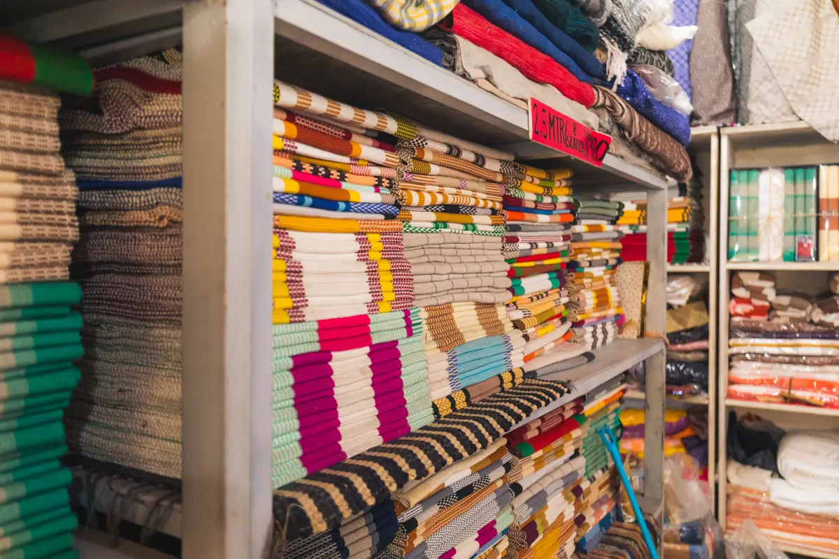 Shelves filled with stacks of neatly folded colorful fabrics and textiles, arranged by type and color, create an organized and vibrant display inside a fabric store—a must-see for anyone following a Vigan guide to explore unique Vigan tourist spots.