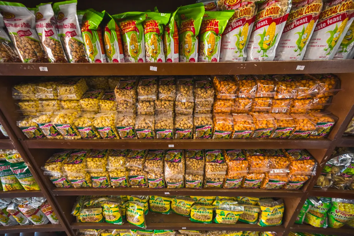 Shelves stocked with various packaged snack products, including popcorn in clear bags and assorted snacks in colorful packaging, organized in rows at a store—perfect treats to enjoy while exploring the best places in Vigan.