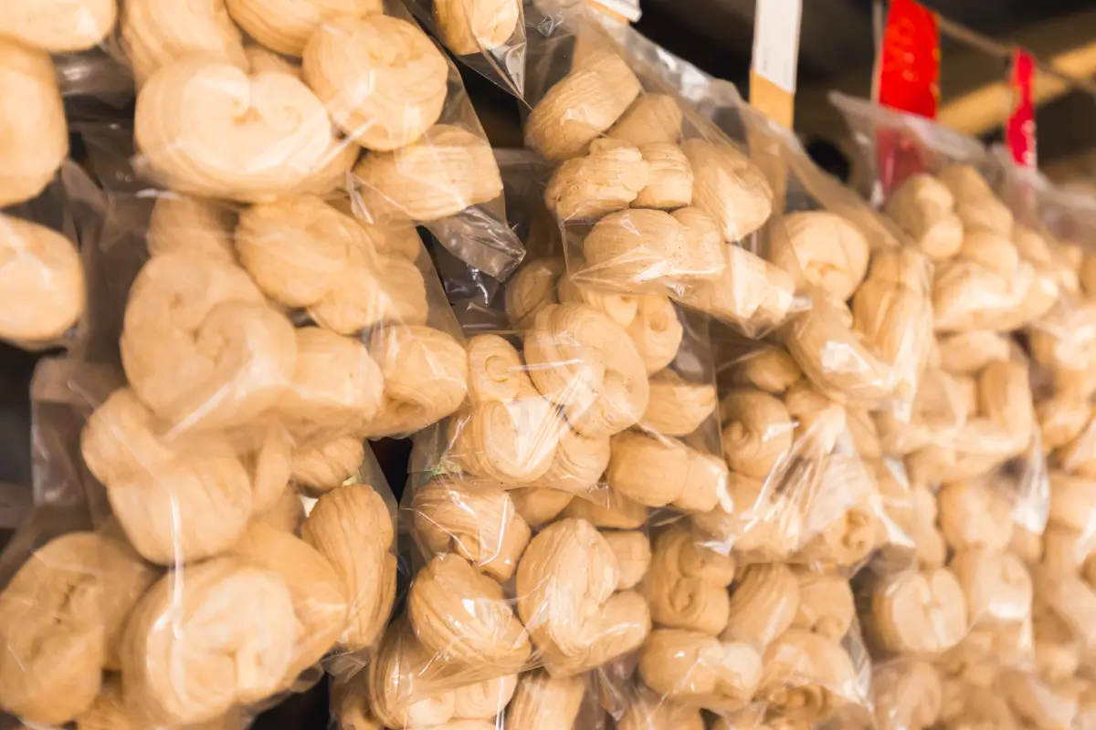 Stacks of clear plastic bags filled with round, light brown bread rolls arranged on shelves—a staple you’ll spot when exploring the Best Places in Vigan and other must-see Vigan tourist spots.